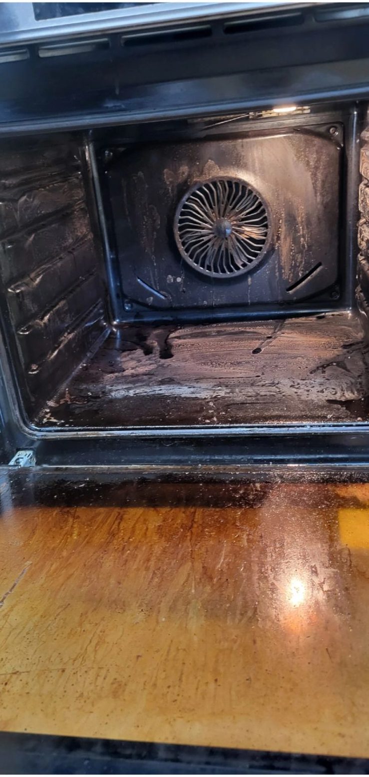 Oven before cleaning: blackened grease on the floor and back panel